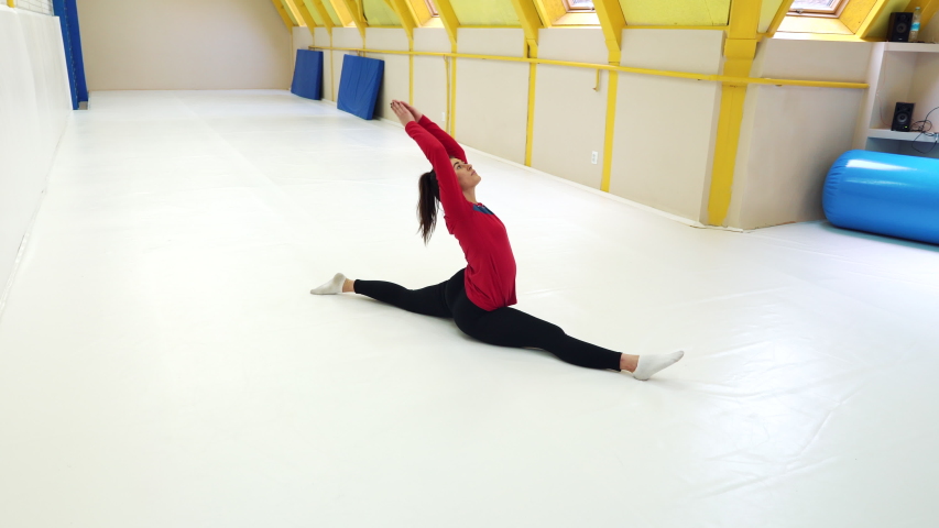 Fit girl doing splits on mats in gym