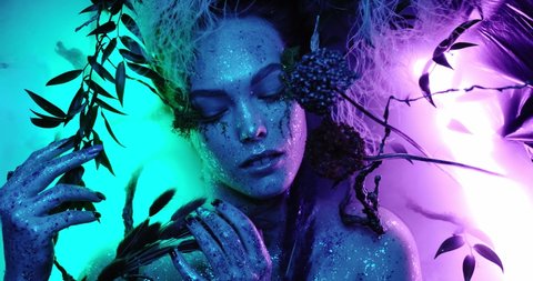 Fantasy world, a fabulous beautiful woman nymph or elf looks at the camera and poses with bright neon colors blue and purple creating magic around her fog and abstract, closeup portrait 4k quality