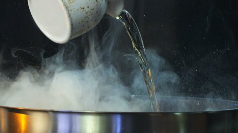 Splashes Oil, drops of water and smoke (vapor) come flying out of pan. Hot Pan Splashing Oil. Boiling Dish Sauce in pan. Oil in pan is spraying Slow Motion.  Red Epic Dragon Camera Cinematic Footage.