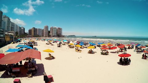 Guaruja - SP, Brazil - November 20, 2019: Sunbathers at Praia das Pitangueiras beach, the main tourist urban beach of the city. Buildings of Morro da Campina hill on the background.