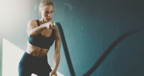 Fit attractive woman working out with battle ropes in the gym, intense focused woman training hard to achieve her fitness dreams : vidéo de stock