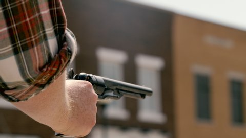 Close on cowboy shooting old gun enveloped in smoke at a shootout