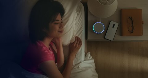 IOT AI smart home concept - Asian woman talk with voice assistant to turn off the lights of house at home while sleeping