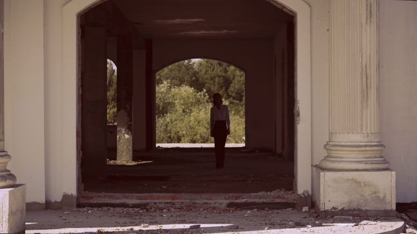 fashionable brunette walking abandoned house view on the terrace with columns in classic abandoned building