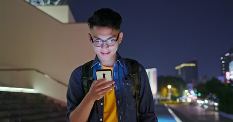 asian young man use smart phone outdoor and watch something interesting on it in the evening