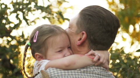 Portrait of father holding child girl in his hands and hugging each other outdoors. Dad cudding and kissing with his daughter. Father's day