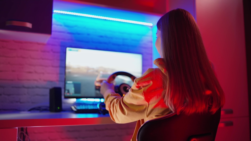 Girl sits in simulator of car. Woman playing on computer with steering wheel