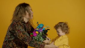 Woman comforting crying kid with flowers on yellow background