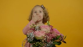 Shocked curly kid looking at flowers and covering mouth with hands