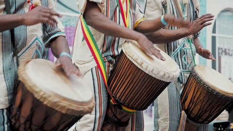 The celebration of the Brazilian carnival in Moscow. African drummers in ethnic clothes playing on djembe drum close up. Musician beats rhythm on african drums. Black artists hit the drums with their