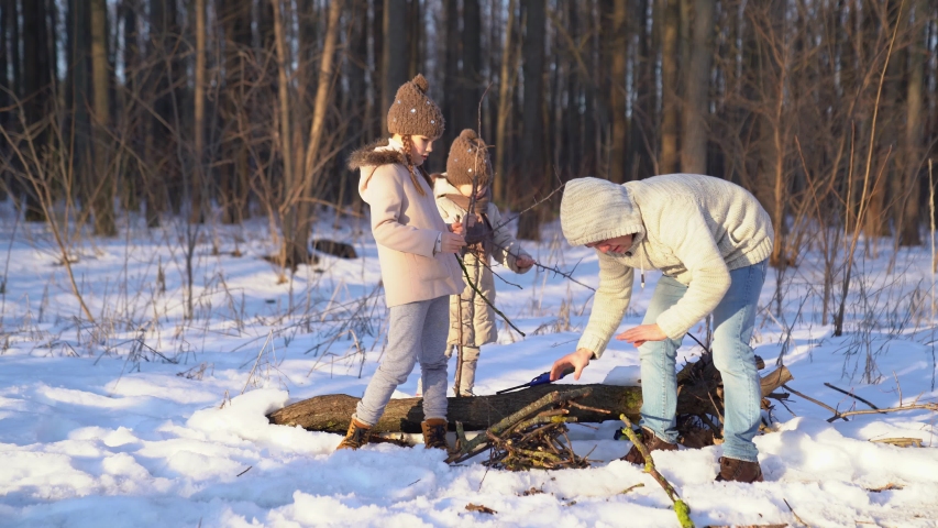 Family in the winter woods breaking branches for a fire