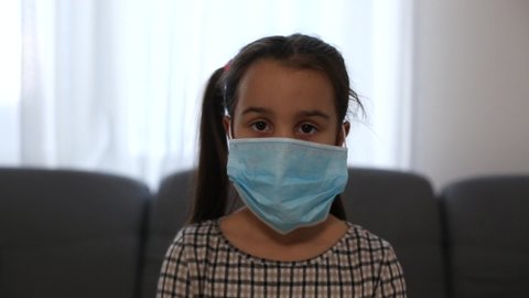 Sick little girl wearing a medical mask against virus closeup lokking at camera - Concept of coronavirus protection