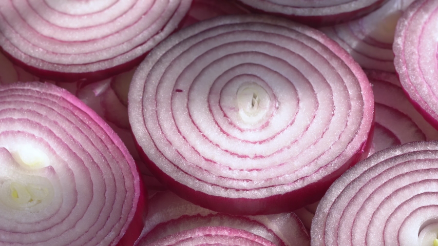 Sliced red onion rings rotating on white in 4K. Closeup top view of healthy food background with vegetable of rich vitamin.