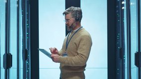 Handsome concentrated IT engineer operator talking via headset analyzing data center internet server cabinet. Cloud computing, digital communications. - Powered by Shutterstock - Get 15% off with code: PIKWIZARD15