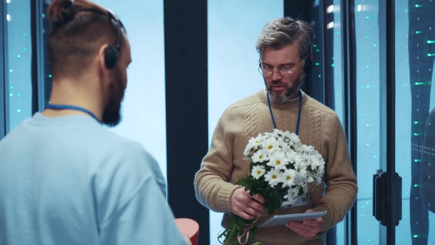 IT specialist gifting a heart-shaped box and flowers to his male colleague valentine at server room. Offended and amazed man rejecting a present fighting back with flowers kicking out. Lgbt. Everyone
