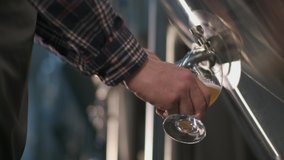 A male brewer pours beer from a beer tank into a glass for tasting. Close-up - Powered by Shutterstock - Get 15% off with code: PIKWIZARD15