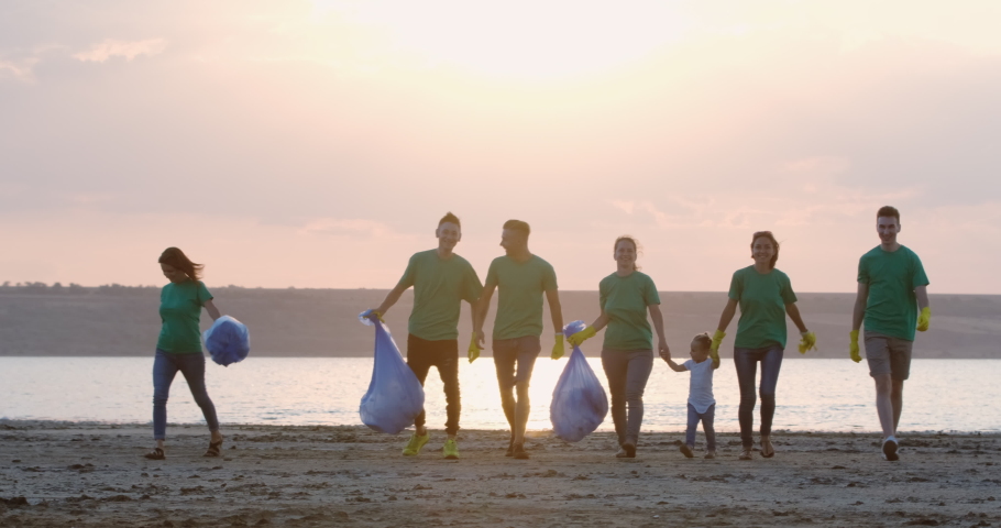 Sorting of the recyclable waste, an optimistic group of volunteers take out the garbage from the beach, volunteers give a high five to each other. Royalty-Free Stock Footage #1047772828
