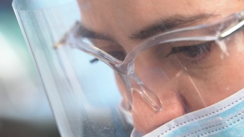 Close-up of a female doctor's eyes through a protective mask and medical glasses during work.