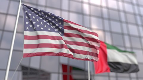 Waving flags of the USA and the UAE in front of a skyscraper