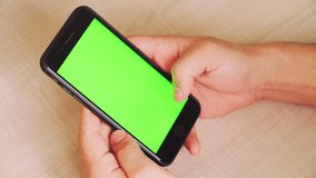guy holding a smartphone in the hands of a green screen, hand of man keeps mobile smart phone with chroma key. on white background.
