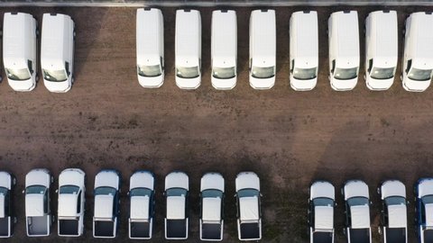 Aerial top down view of the dealership or customs terminal parking lot with a rows of new commercial cars
