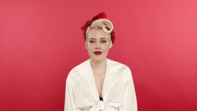 Blonde pin up girl laughing and shaking head on pink background