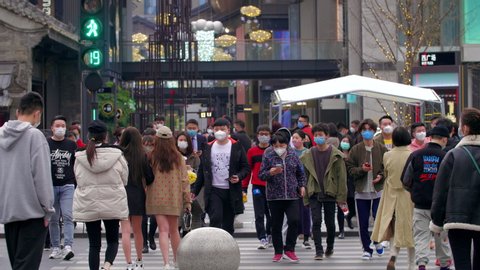 Chengdu, Sichuan/China-March 4th 2020:Crowd walking zebra crossing wear protective mask for protect Coronavirus, during  Covid 19 virus outbreak and PM2.5 air pollution at Taikoo Li commercial town