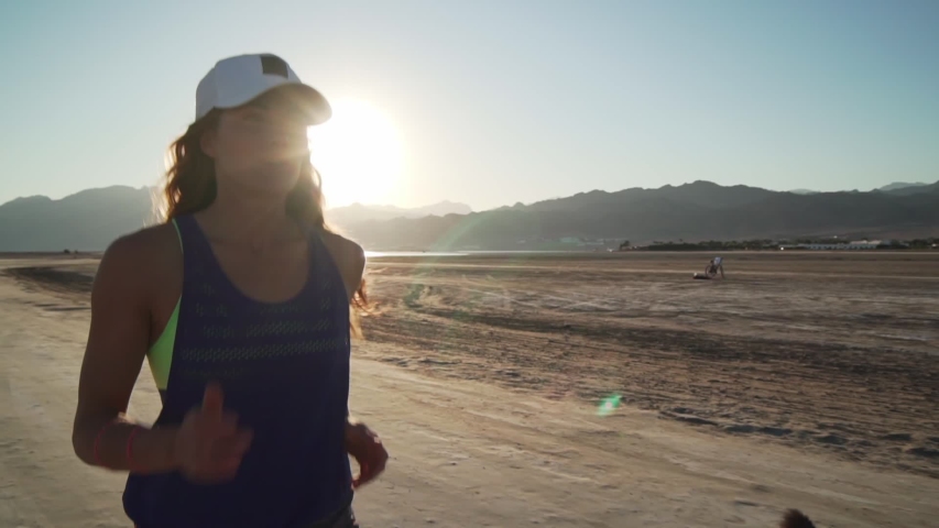 Portrait of caucasian girl jogging in dry desert at sunrise rapid slow motion