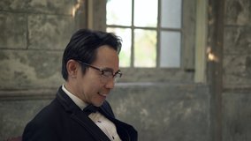 Asian groom sitting on a red chair using smartphone are smiling and happy in studio. Handheld shot. Real life - Powered by Shutterstock - Get 15% off with code: PIKWIZARD15