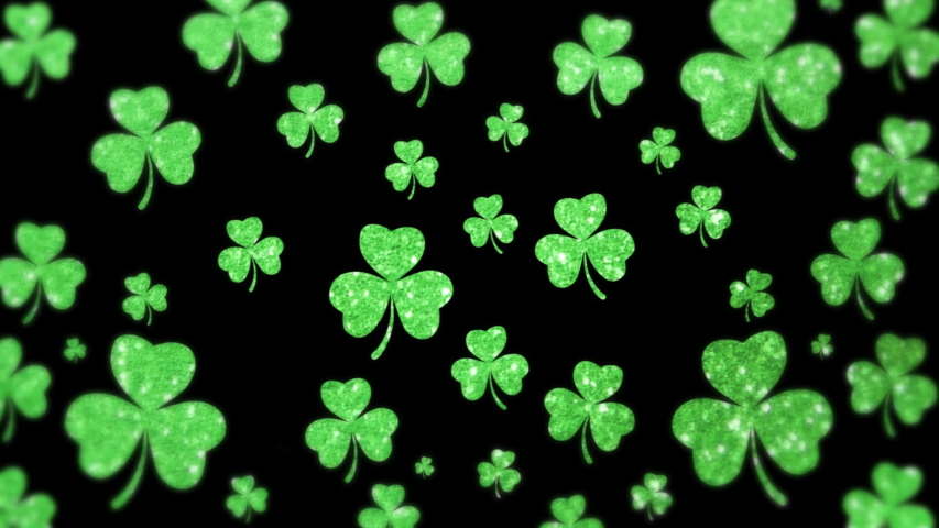 Animation of St Patricks Day multiple shimmering floating green shamrocks with a man opening his shirt showing an Irish flag on in the background. Celebration of Irish culture concept digitally