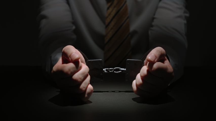 Businessman Wearing Formal Attire Puts His Handcuffed Hands On A Black Table | Shutterstock HD Video #1047823447