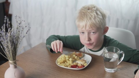 An albino boy eats lunch at home at the table.