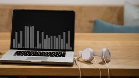 Animation of moving peak levels indicator of graphic equalizer displayed on screen of laptop computer on desk with headphones. Global communication modern technology concept digitally generated image. - Powered by Shutterstock - Get 15% off with code: PIKWIZARD15