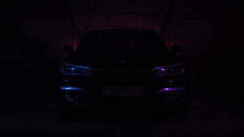 TOMSK, RUSSIA - July 26, 2019: BMW 7 Series optics view through smoke, black background. Color lighting. Adaptiver LED