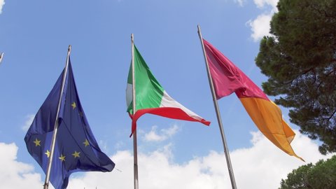 Three flags waving in wind against blue sky. Close up of Italian, European Union and flag of Rome city on Capitoline hill