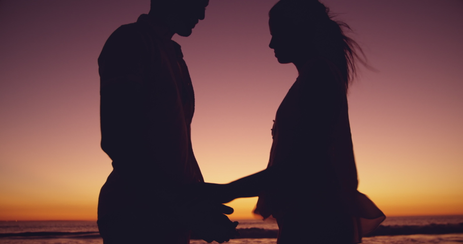 Side view of a young mixed race couple enjoying free time embracing on a beach by the sea at sunset