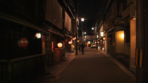 Kyoto, Japan - April 16, 2019: Street in Gion district at evening night road people by restaurant walking red lanterns handheld pov panning