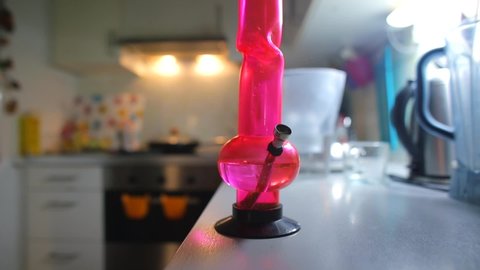 Closeup of bong smoking in the apartment kitchen. A man smokes medical marijuana. The concept of mental relaxation.