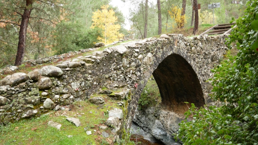 Child crosses the Elia Venetian Bridge. A river flows under the bridge. Climbing uphill. This is an old stone bridge without handrails.