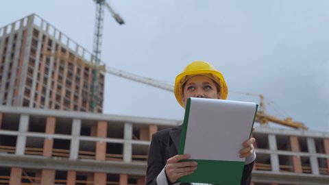 female engineer compares the progress of construction with the plan. The girl is pleased with the results. 4K