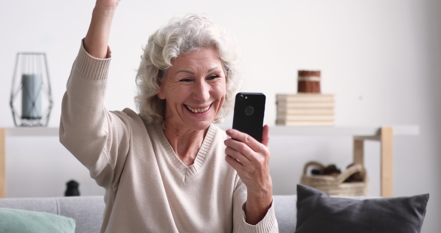 Amazed senior lady celebrating mobile win concept. Overjoyed 70 years old woman using smartphone reads good news in sms. Happy lucky elder female customer feels excited gets shopping sale offer | Shutterstock HD Video #1047850687