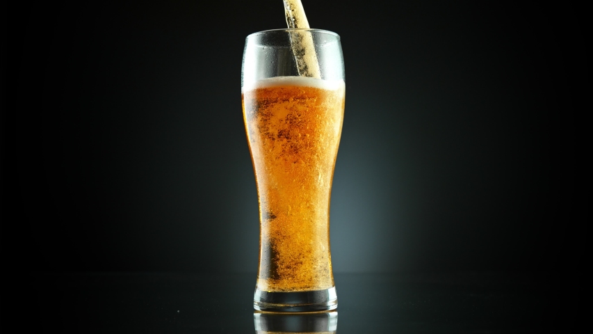 Super Slow Motion Shot of Pouring Fresh Beer into Glass on Black Background at 1000fps. Royalty-Free Stock Footage #1047852031