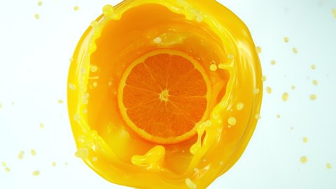 Super Slow Motion Shot of Orange Slice Splashing into Orange Juice Isolated on White Background at 1000fps.