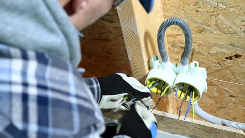 Male Electrician Binds and Organizes Alike Wires In Outlet In New Construction Site.