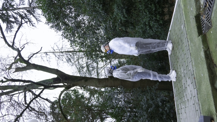 a man and a woman in protective suits and respirators, go to the Park.