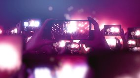 Fans are recording videos on smartphones. A lot of smartphones. Live Stream. Stories. The crowd watches a concert, sings, jumps. Strobing stage lights. Happy people are watching an amazing concert