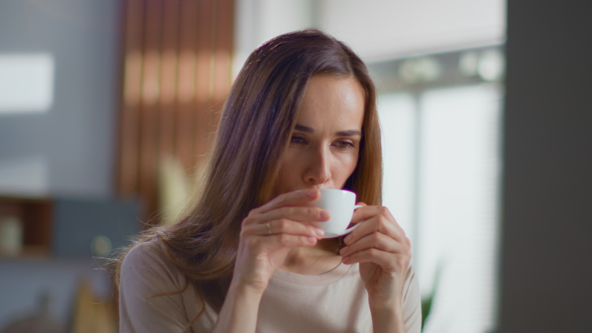 Portrait of satisfied woman drinking tea on kitchen. Attractive lady enjoying cup of coffee at home in slow motion. Smiling woman holding cup of tea in hands at morning | Shutterstock HD Video #1047895516