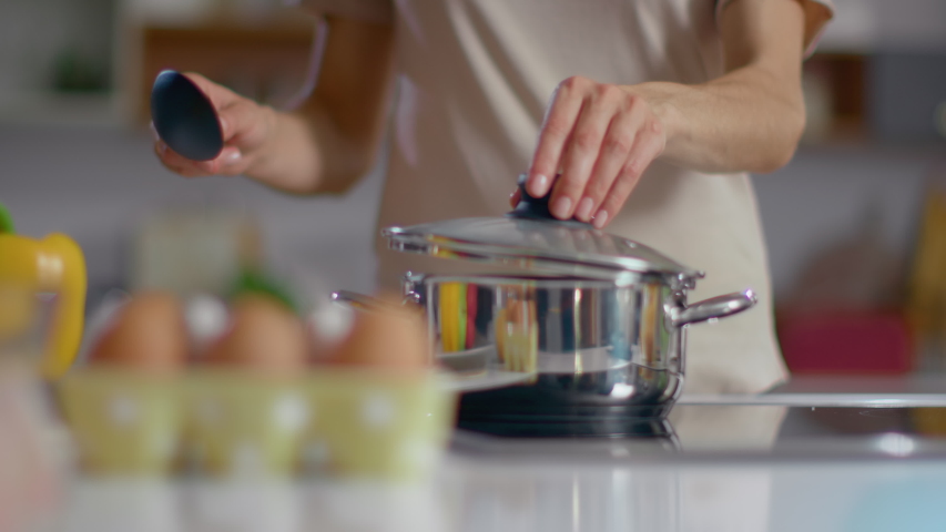 Unrecognizable woman cooking soup on kitchen. Close up of housewife stirring soup with spoon at home in slow motion. Woman chef standing at stove on domestic kitchen | Shutterstock HD Video #1047895558
