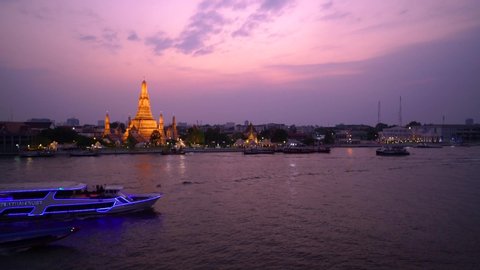 13, February 2020 : The view of WAT ARUN temple pagoda Bangkok Thailand evening sunset with sunbeam and perfect cloud one tourism boat moving in front at Chaopraya river wide angle view