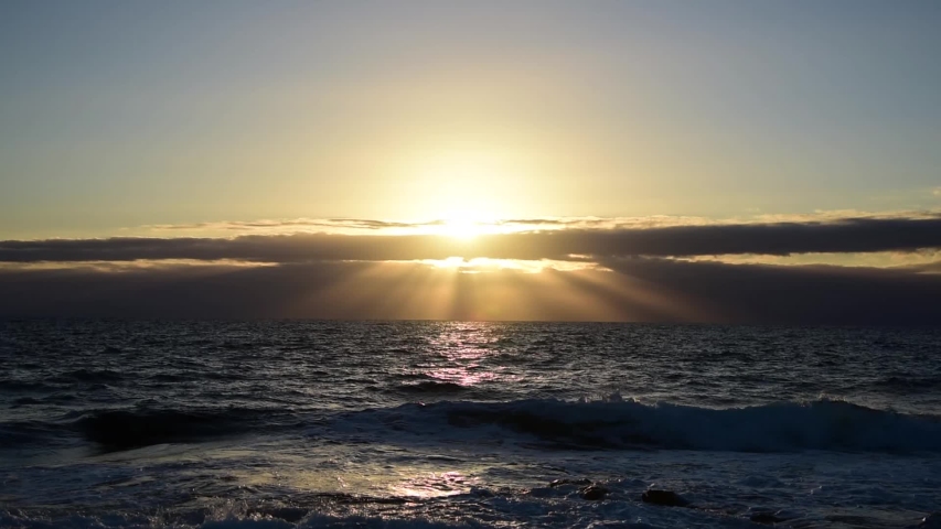 Small waves and shining sun in Alghero shore at sunset. Sardinia, Italy